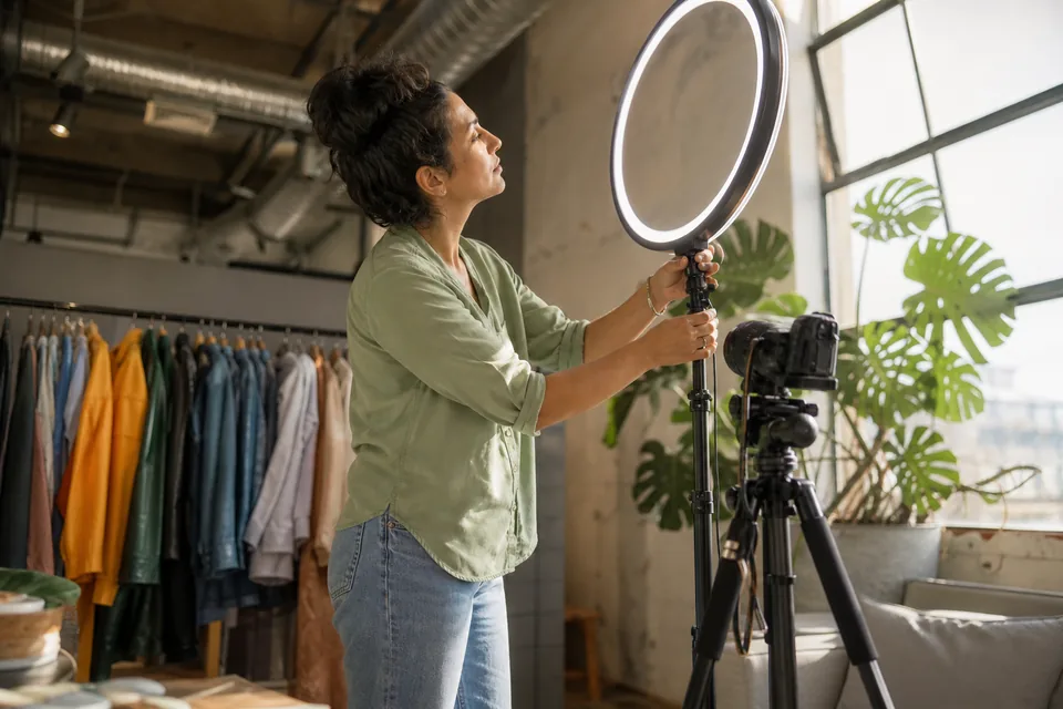 Creator adjusting a ring light next to a camera before recording a members-only video for her fans