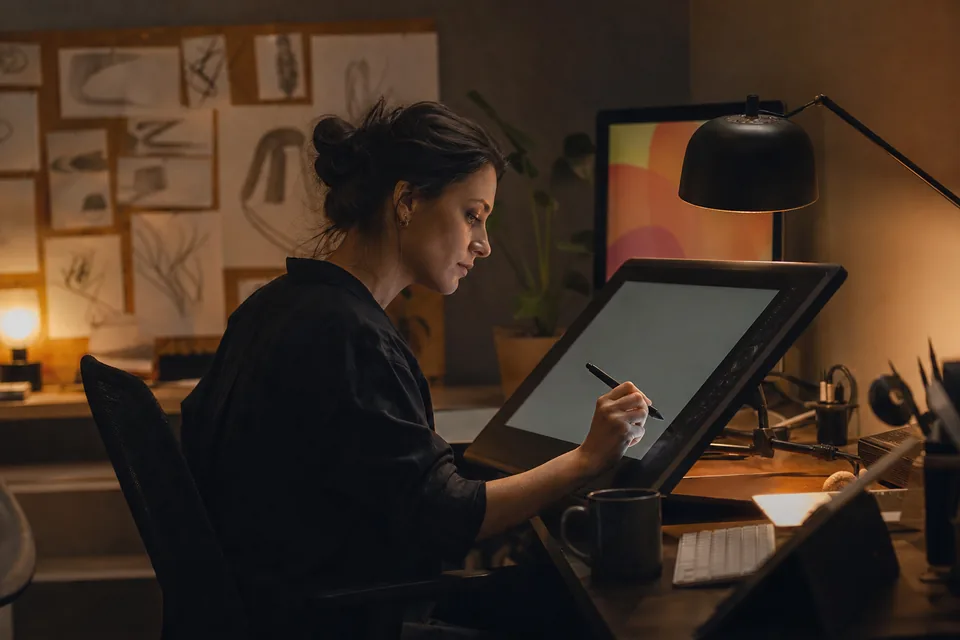 An illustrator working late at a drawing tablet in a home studio