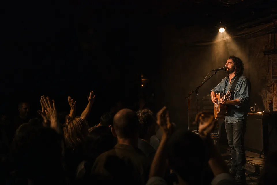 A singer on a small club stage under a warm spotlight
